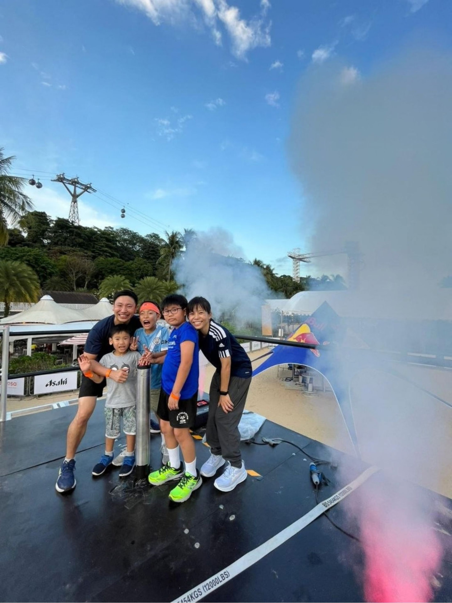 A family smiling together beside an obstacle-course finish with smoke rising around them