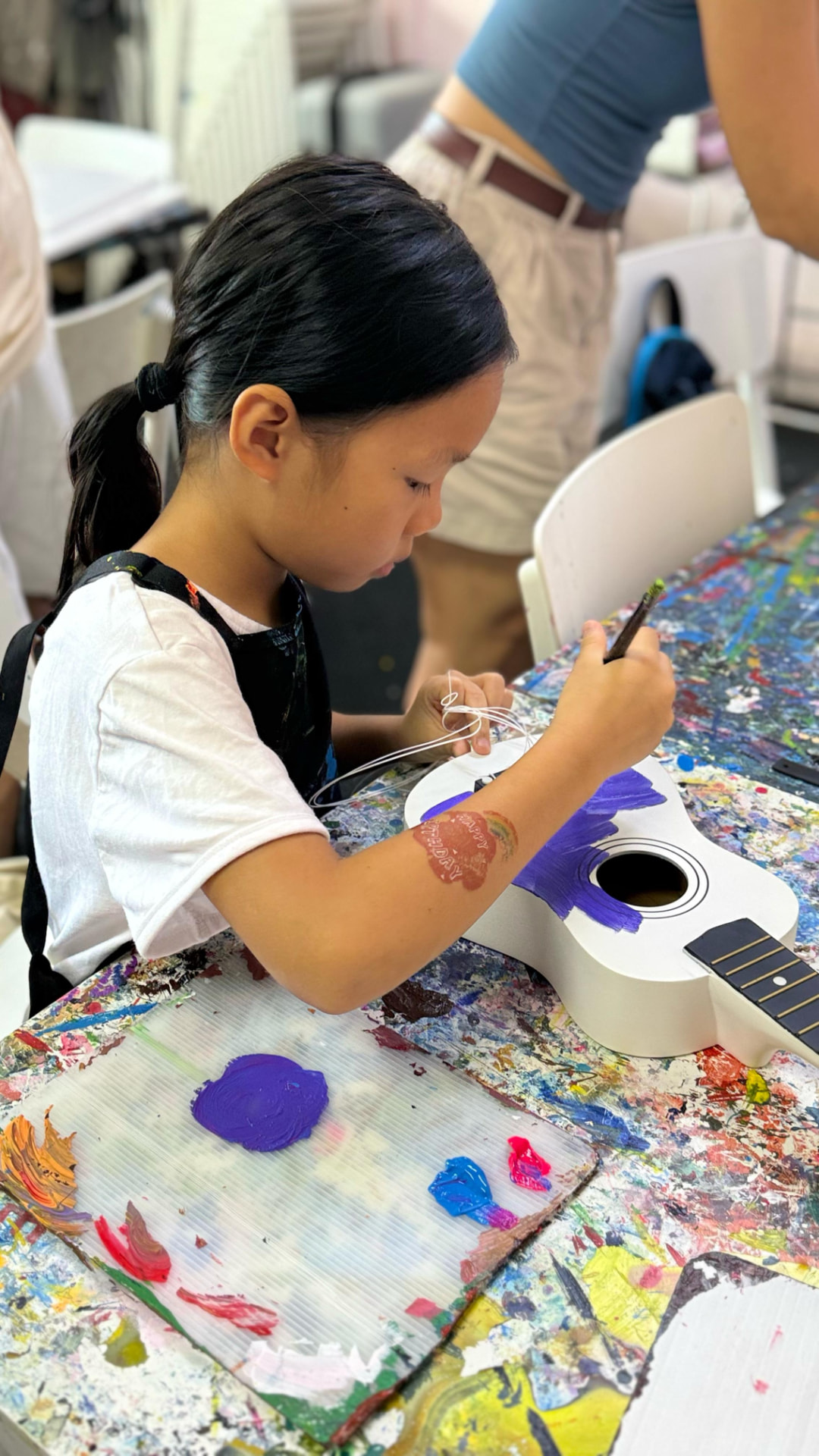 A young participant painting a ukulele during an urban art workshop