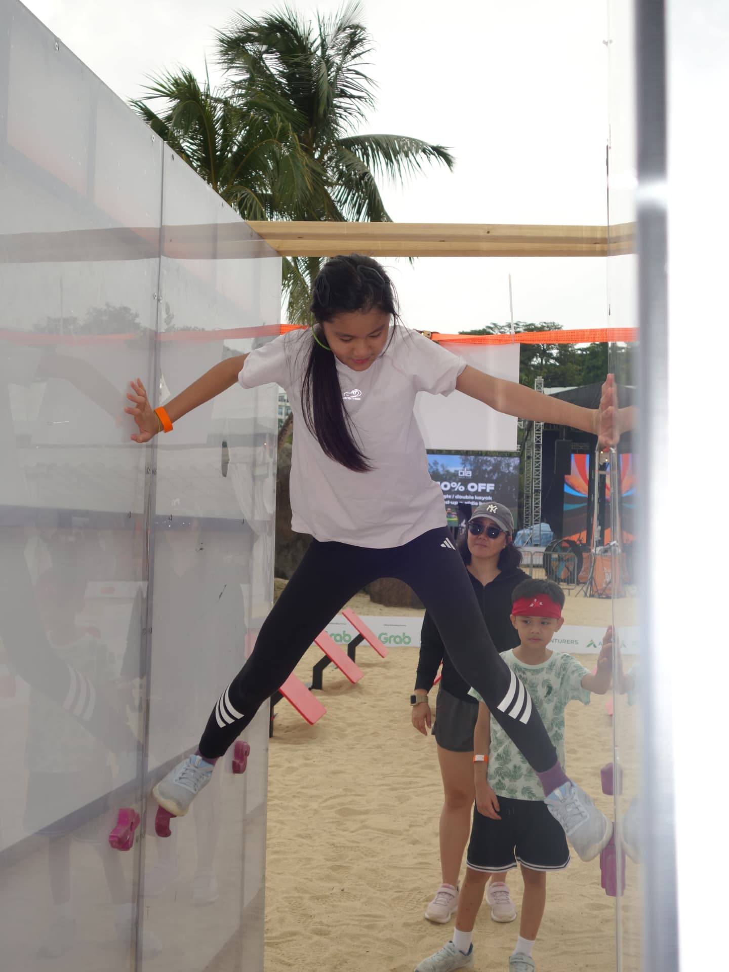A girl bridging a gap between two clear panels on an obstacle course