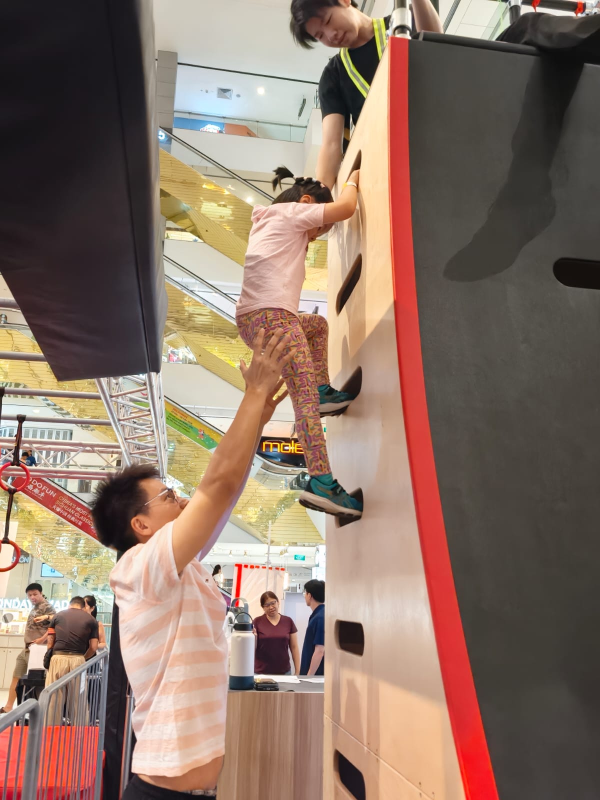 A boy pulling himself over a warped wall on a ninja course