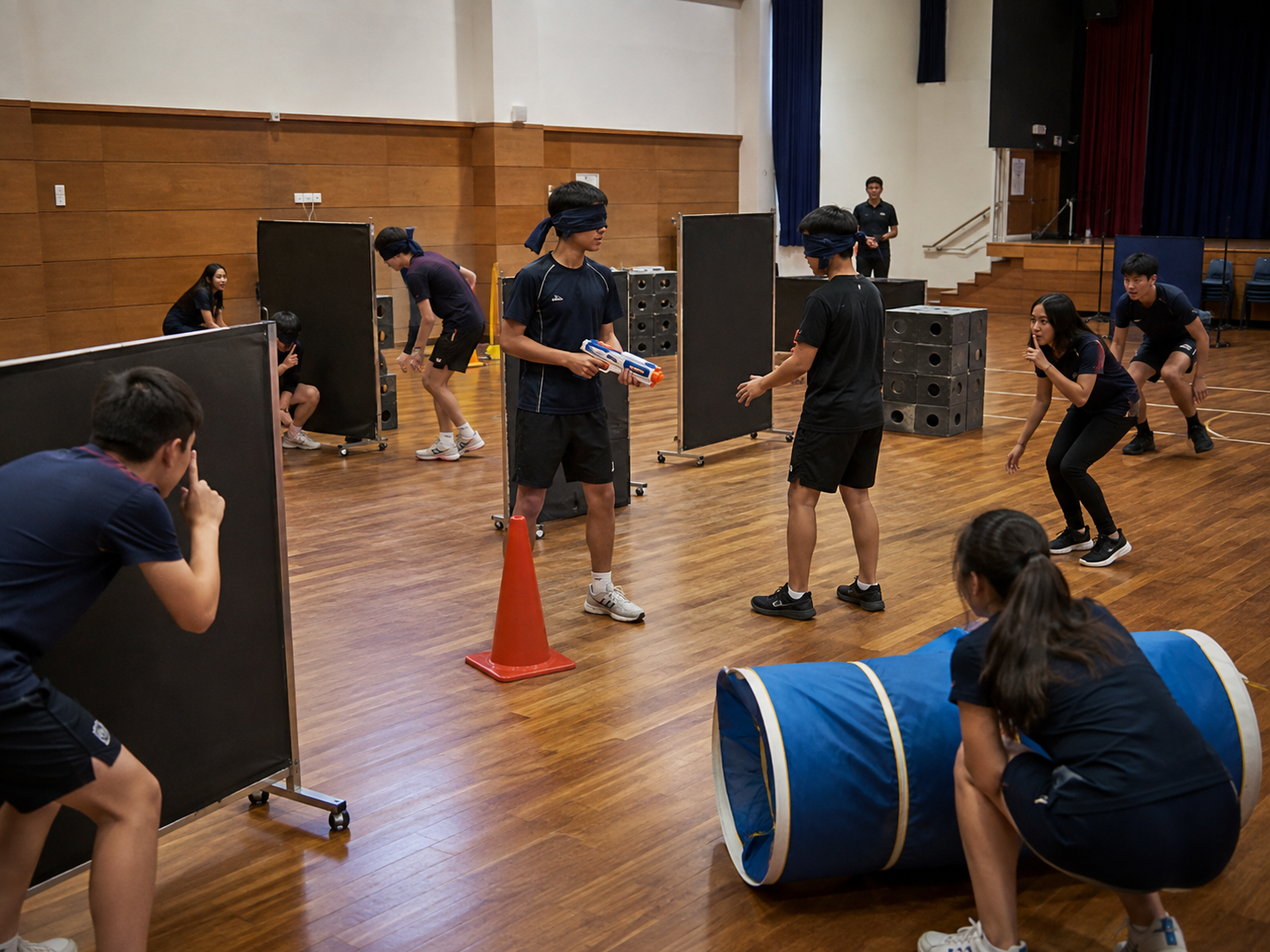 Students working blindfolded through a course in a school hall.