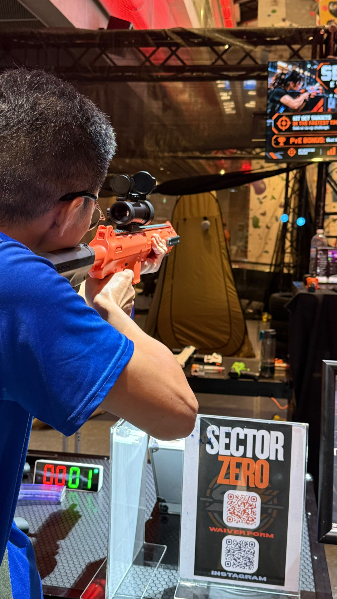 A player taking aim at the Sector Strike target range beside the game signage.
