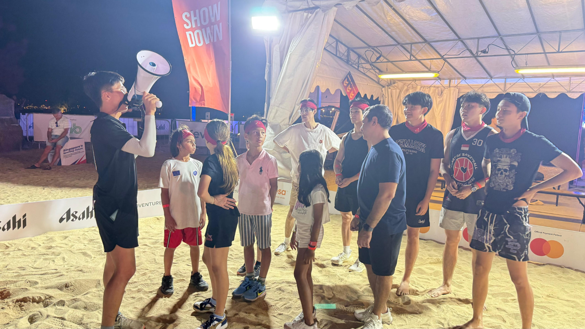 A crew member briefing a group of kids and teens under floodlights before a Shadow Tag run